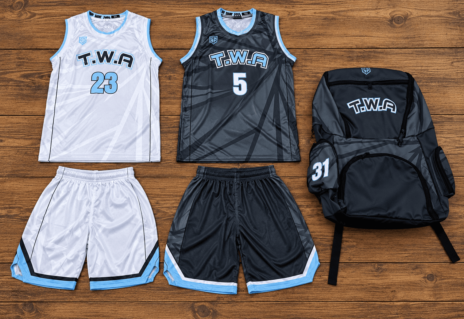 White and charcoal T.W.A basketball jersey and shorts sets with light blue trim and a matching backpack.
