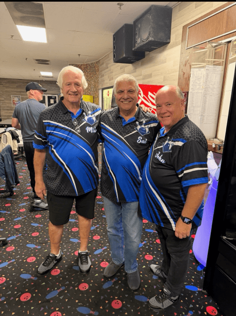 Three Gutter Balls bowlers wearing matching blue and black custom bowling shirts with personalized names on the front.